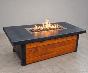 Timberline GFRC concrete fire table by Castin Crete Designs — black concrete top with cedar wood base on brick patio